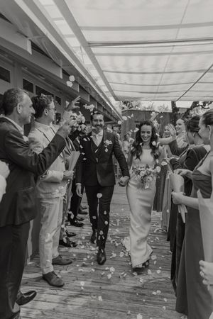 A sequence of black and white wedding photos showing a joyous celebration with guests throwing confetti in an indoor venue.