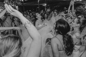 Black and white photo of an energetic crowd dancing and raising their hands on a packed dance floor during a party.