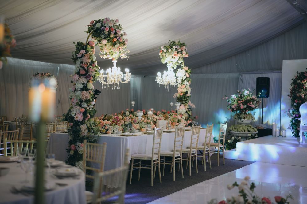 Luxurious white tent wedding reception with floral arches, crystal chandeliers, and elegant table settings.