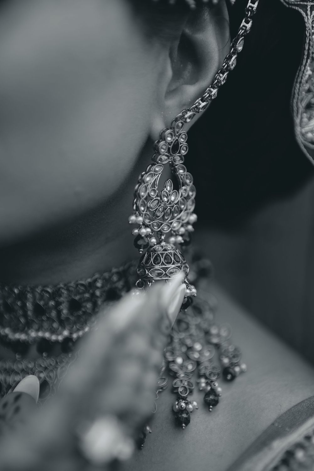 Close-up of an ornate silver and crystal wedding earring with intricate details and pearls.