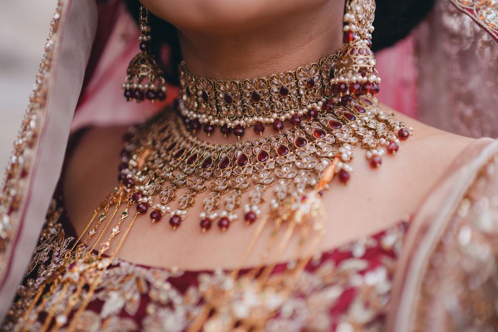 Close-up of ornate traditional Indian bridal necklace with intricate gold work and red gems.