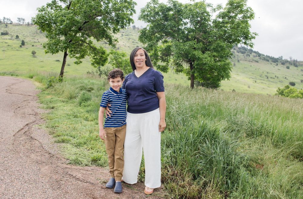 Family members walking and posing together on a nature trail with green hills in background.