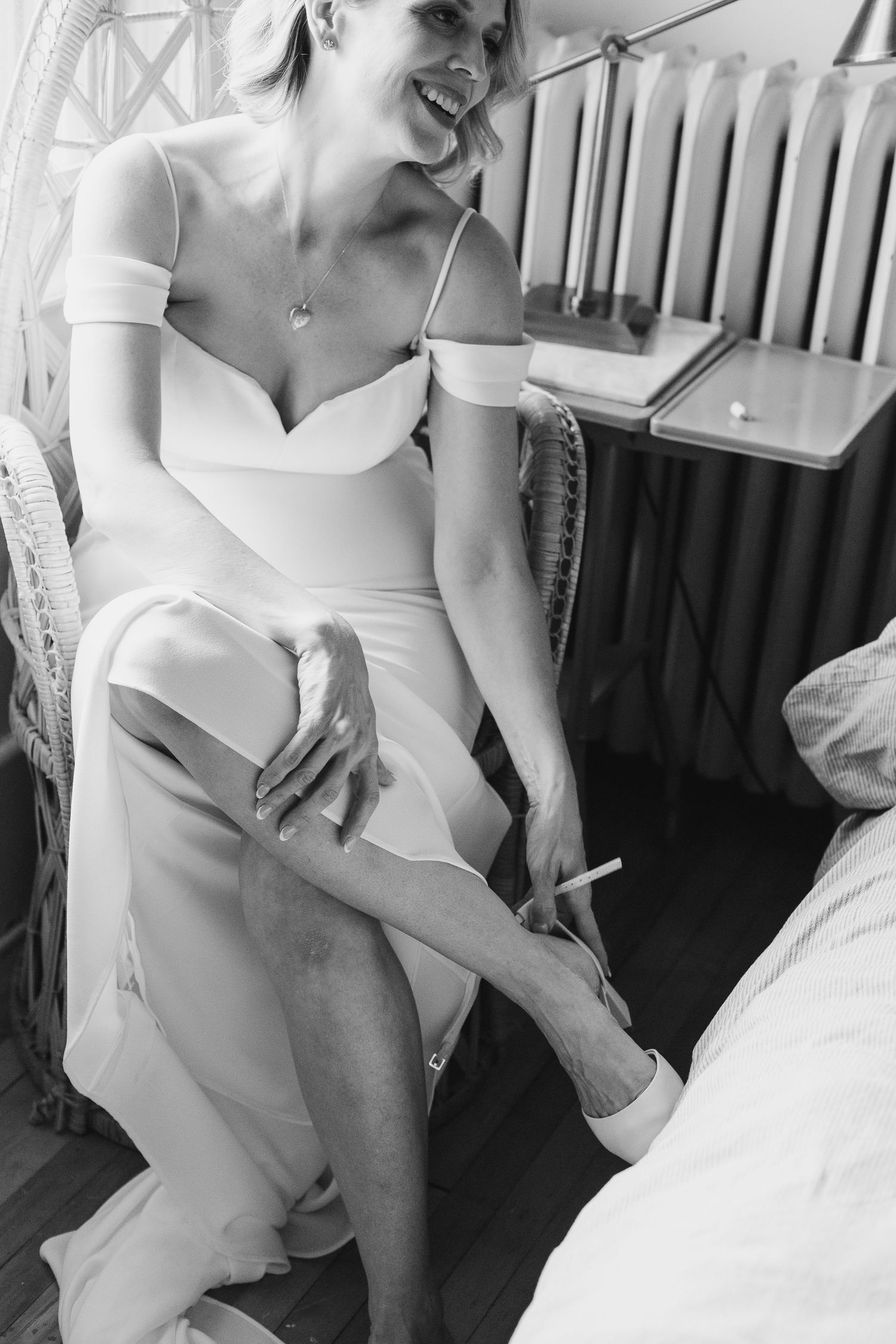 bride wearing her dress putting on her shoes on her weddingday