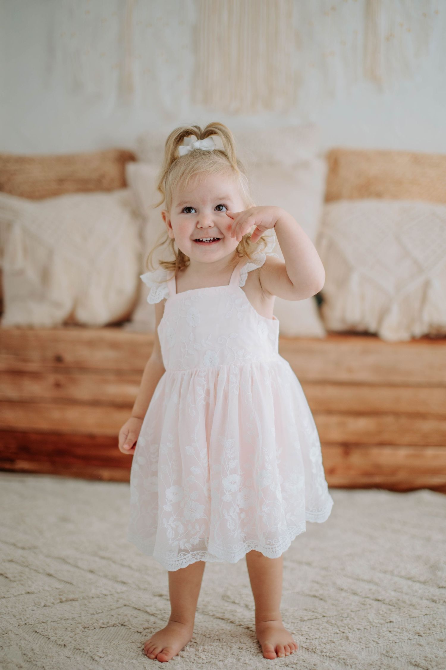 A joyful moment captured as a small figure in a white lace dress dances barefoot on a light carpet.