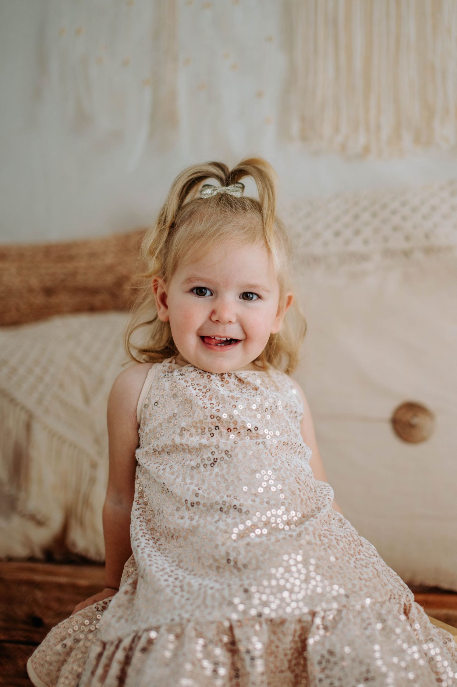 A close-up portrait of a child in a sparkly sequined dress against a neutral-toned background.