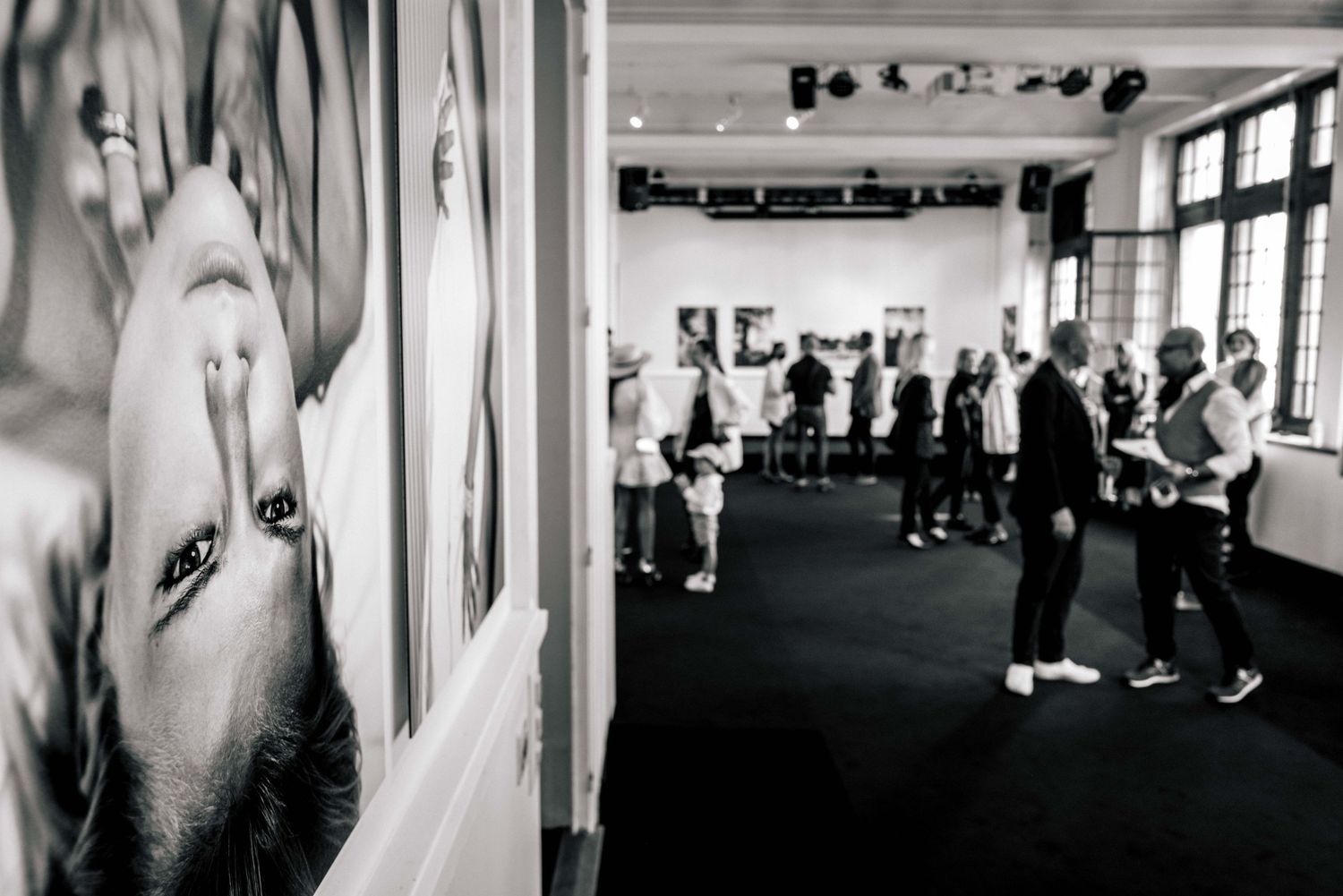 Black and white photo of a fitness class with people exercising in Exhibition hall while artwork hangs on the studio walls.