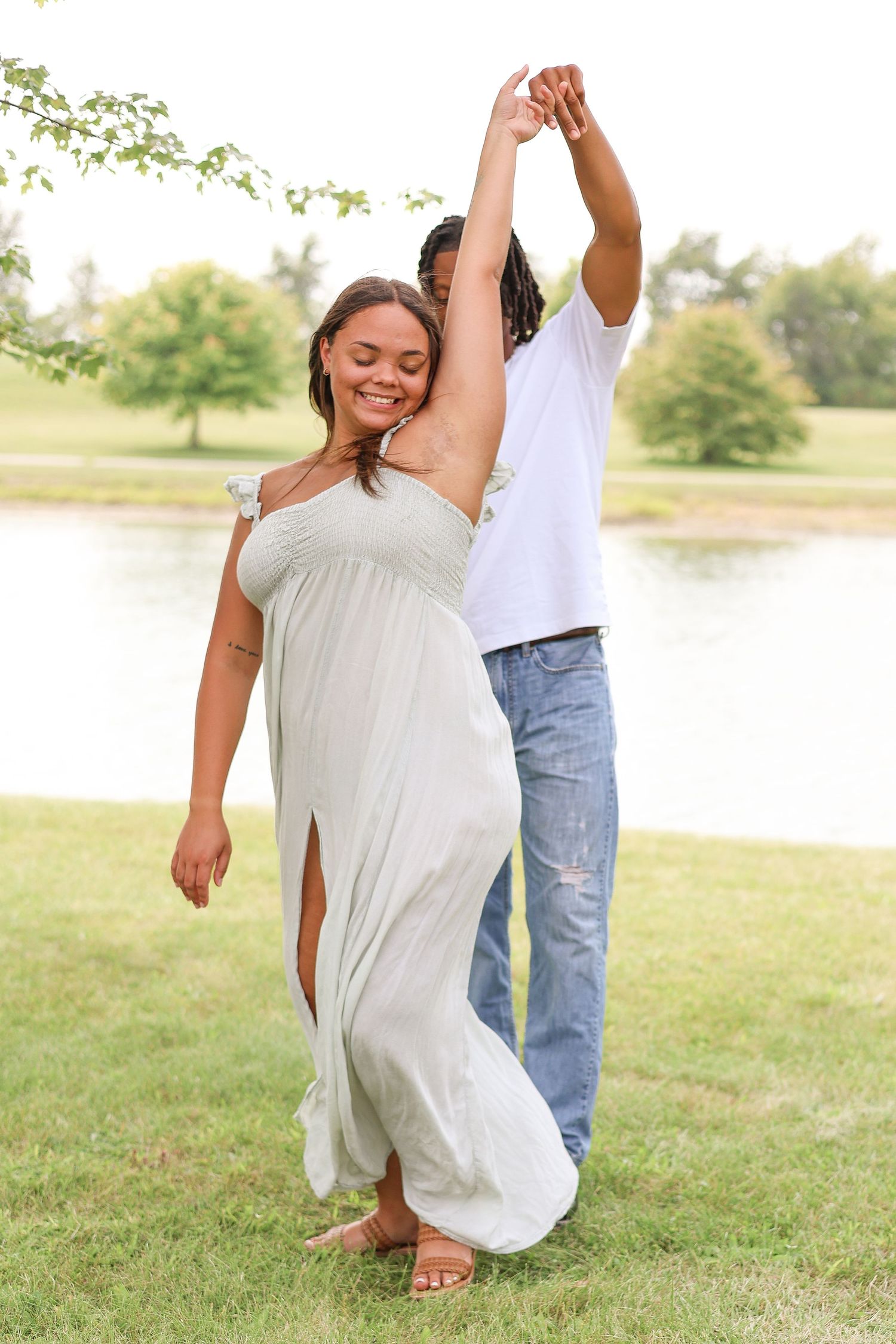 A couple dancing together in coordinated outfits by a lakeside setting.