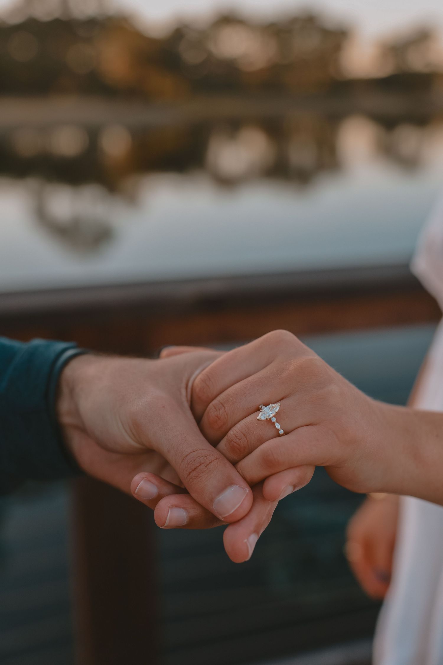 Close-up of elegant marquise diamond engagement ring on womans hand at sunset.