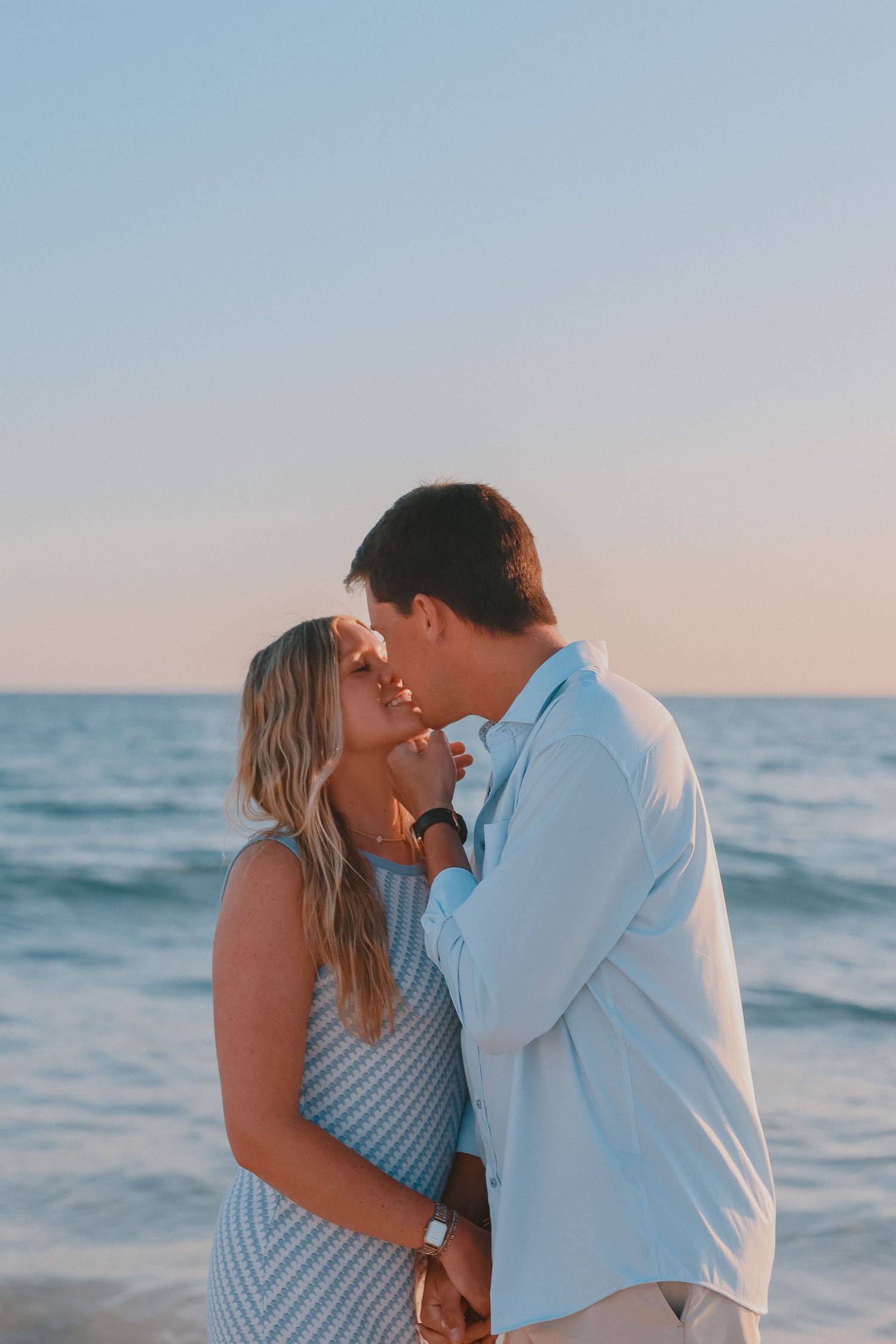 Romantic couple sharing an intimate moment on a beach at golden hour.