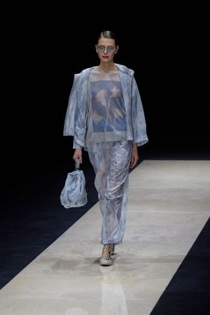 Metallic blue coordinated outfit with matching bag presented on stark white runway.