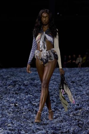 Runway model wears knitted chevron pattern top with asymmetrical skirt and colorful accessories.