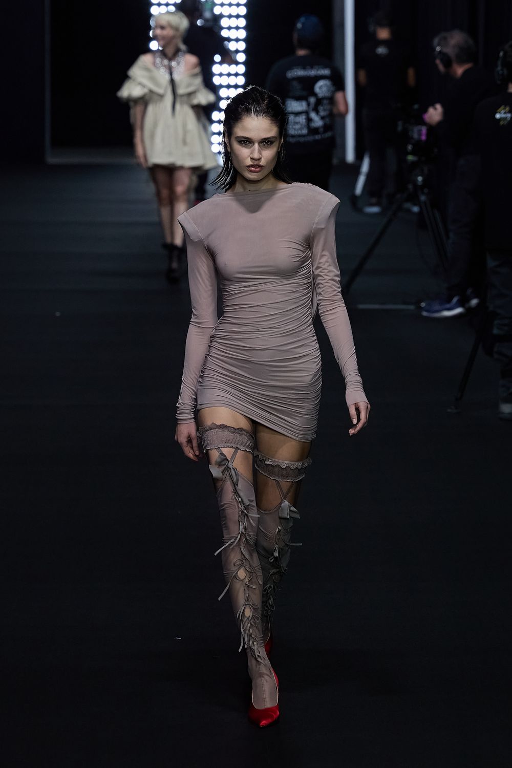 Model presents elegant draped one-shoulder gown in cream with thigh-high slit.