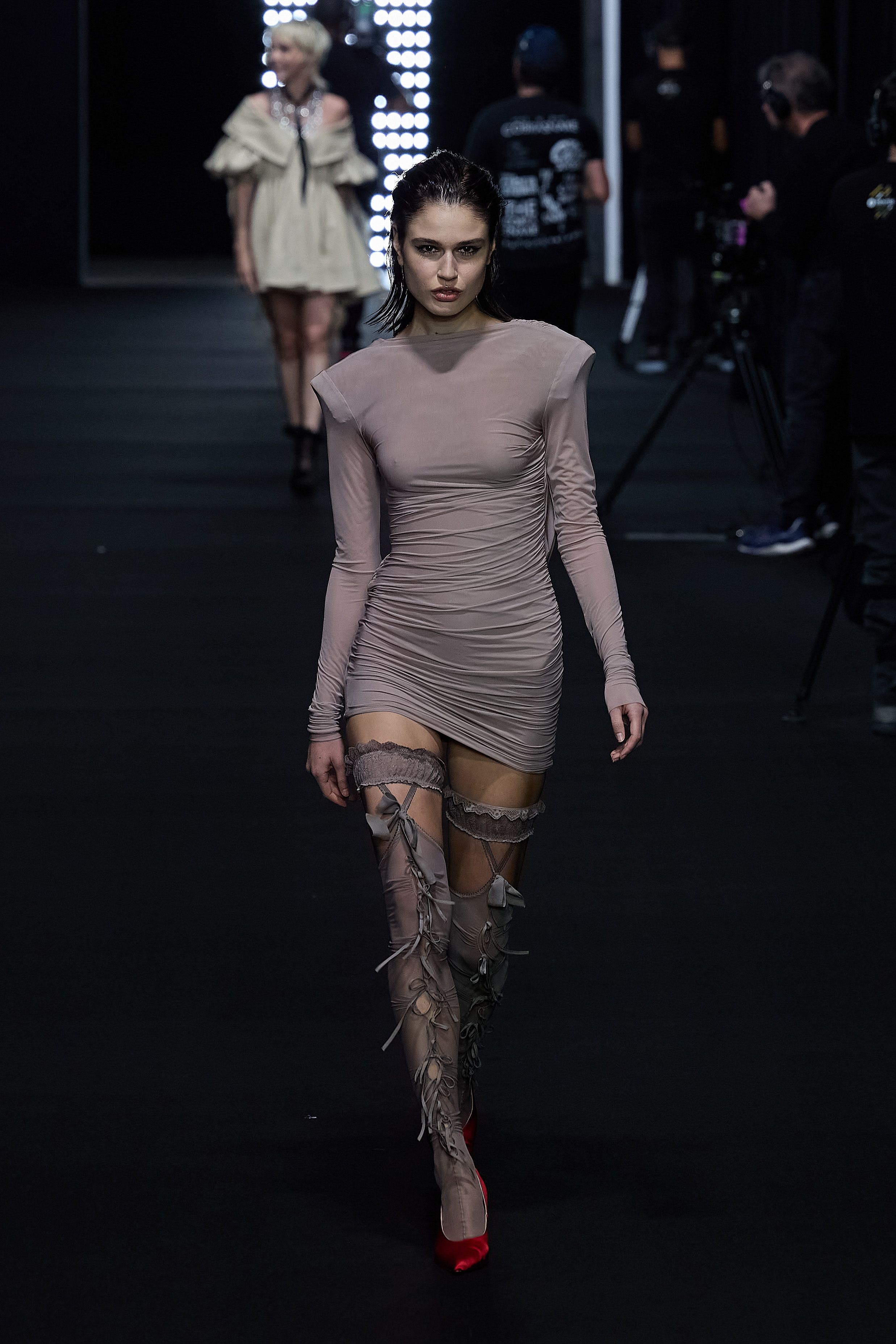 Model presents elegant draped one-shoulder gown in cream with thigh-high slit.