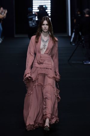 Two models showcase avant-garde designs featuring white ruffled shirt and black textured outfit.