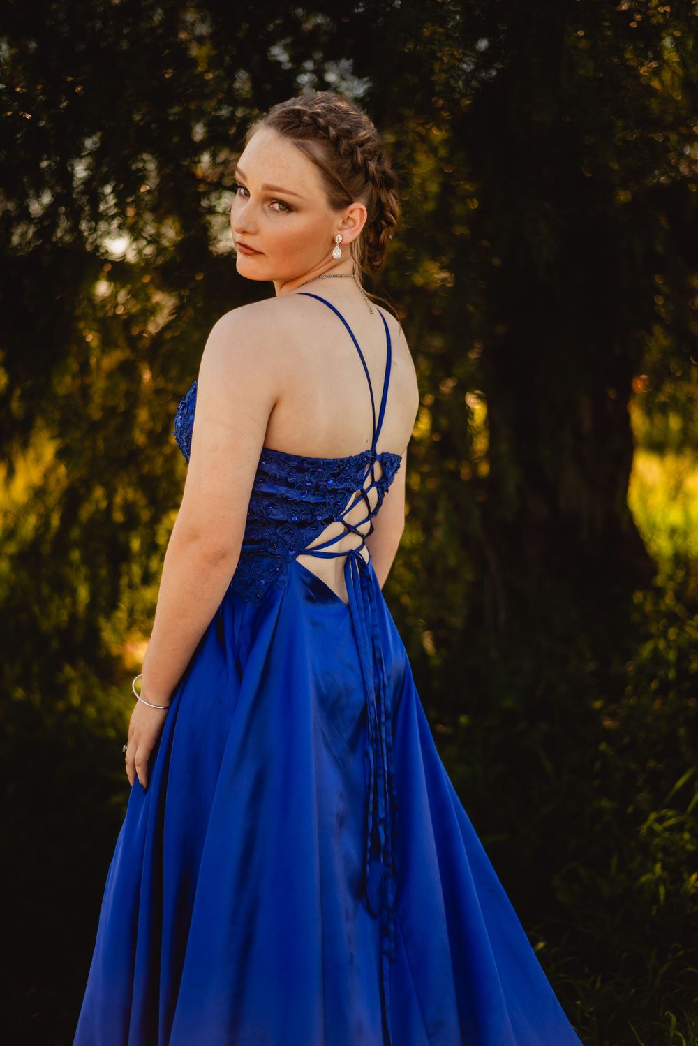 Elegant formal dress with detailed back lacing photographed at golden hour.