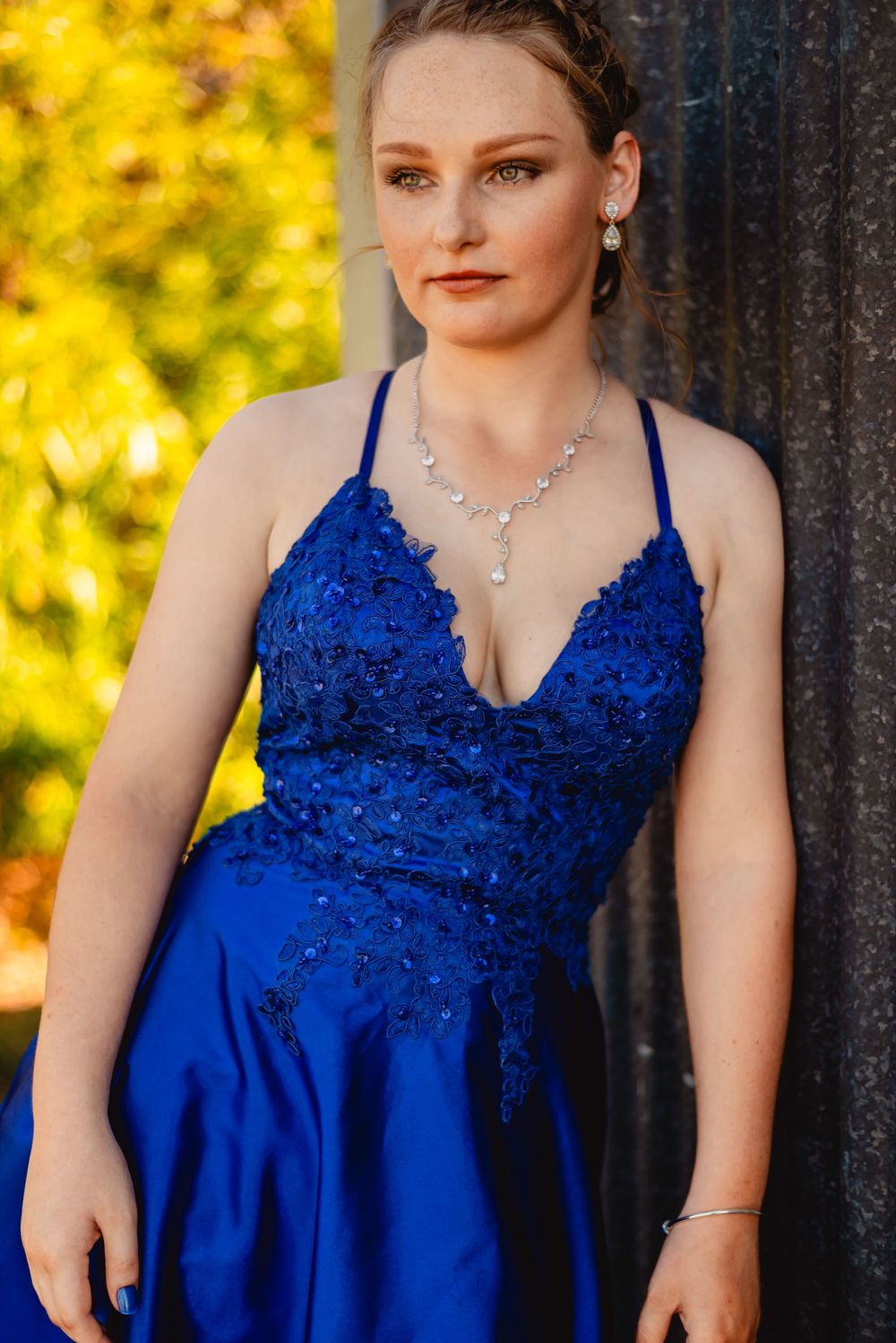 Close-up portrait showcasing a royal blue sequined formal gown with delicate jewelry.