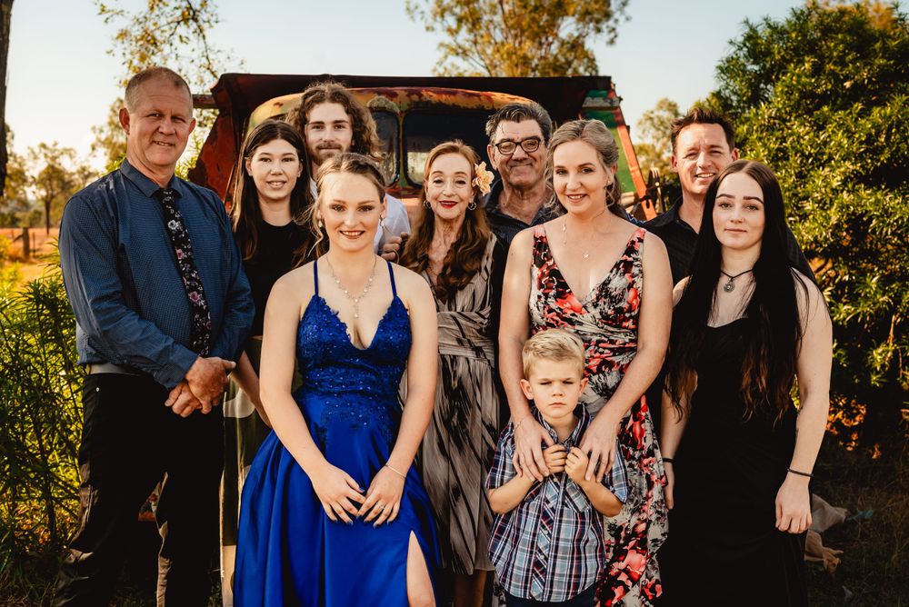Large family group poses together for formal portrait in front of vintage truck.