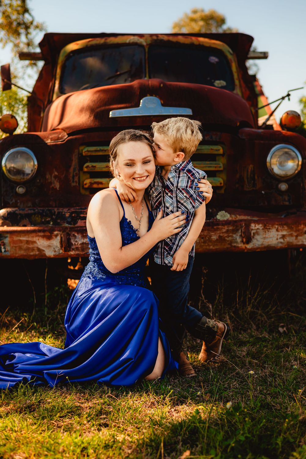 Heartwarming moment in front of vintage truck wearing elegant blue formal dress.