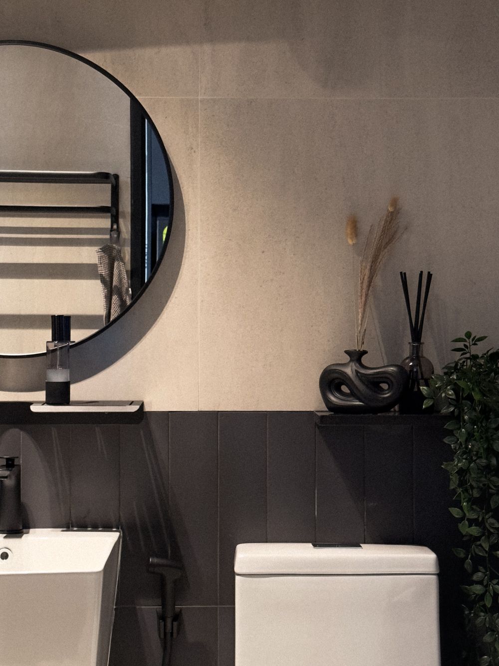 Elegant bathroom featuring a round mirror, white fixtures, and dark wall paneling with decorative elements.