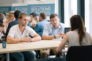 Business meeting scene at a conference table with Solutions banner in background.