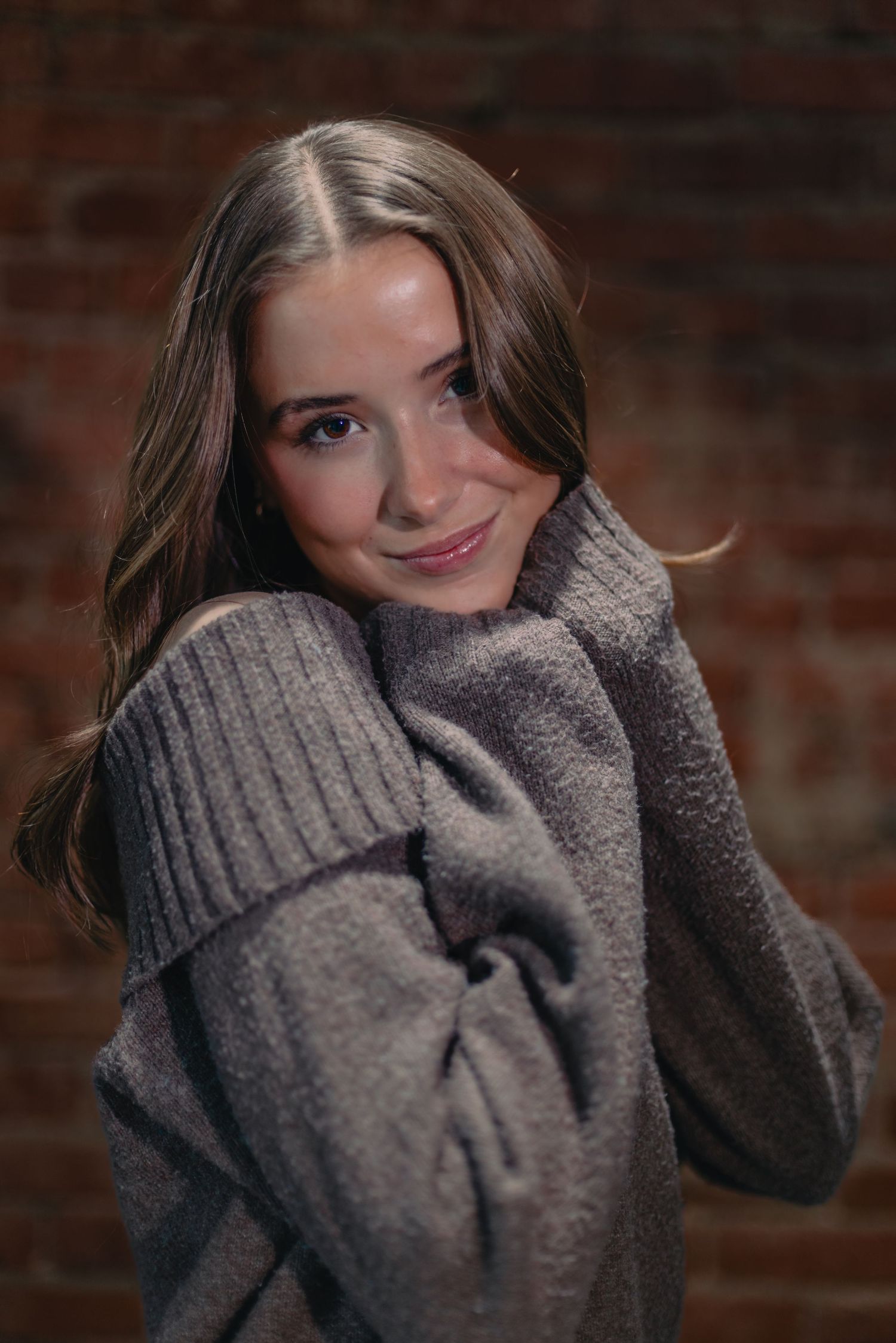 A person wearing a cozy gray turtleneck sweater poses against a brick wall in a series of casual shots.