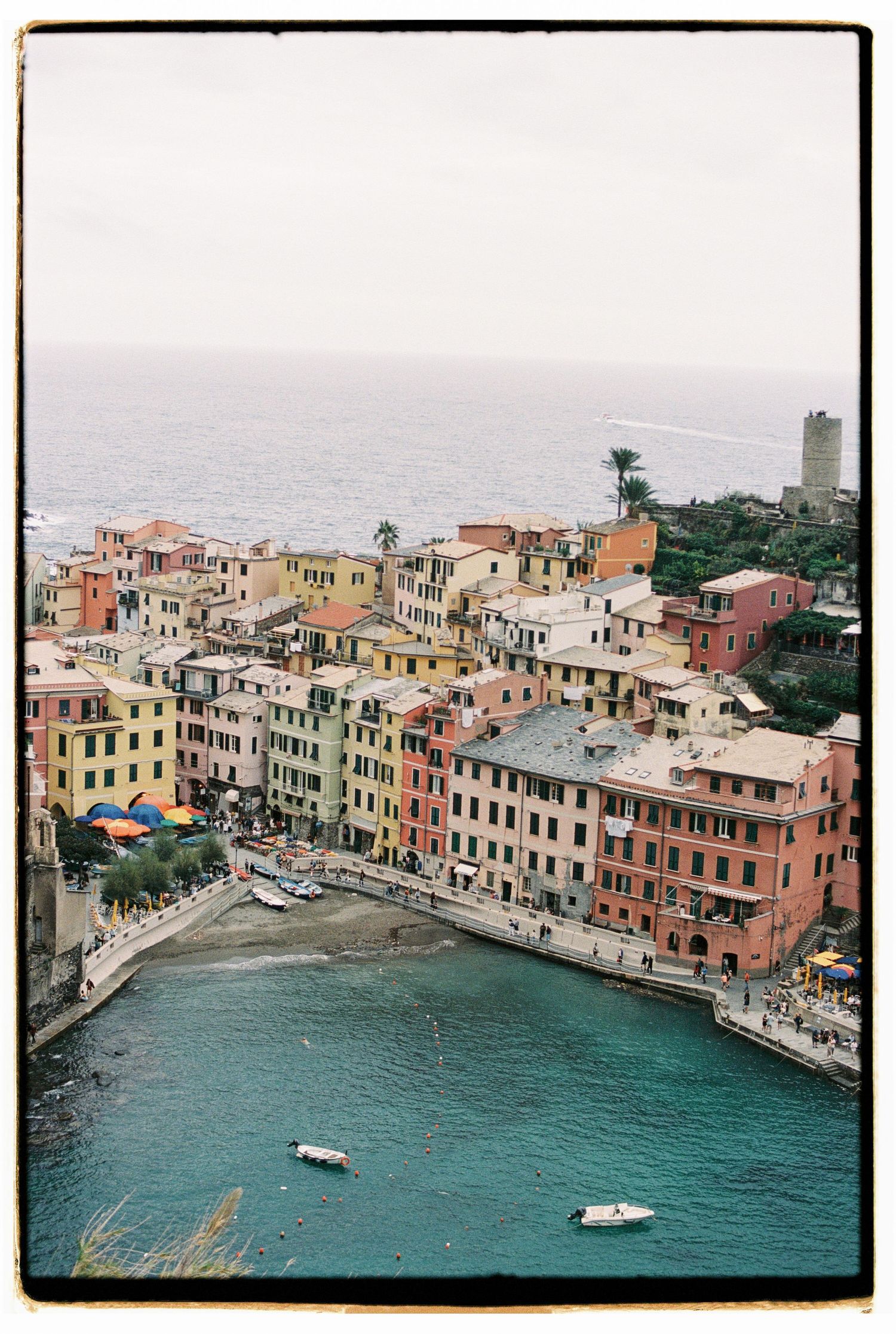 Colorful houses of Vernazza in Cinque Terre overlooking the Mediterranean Sea with boats in the harbor.