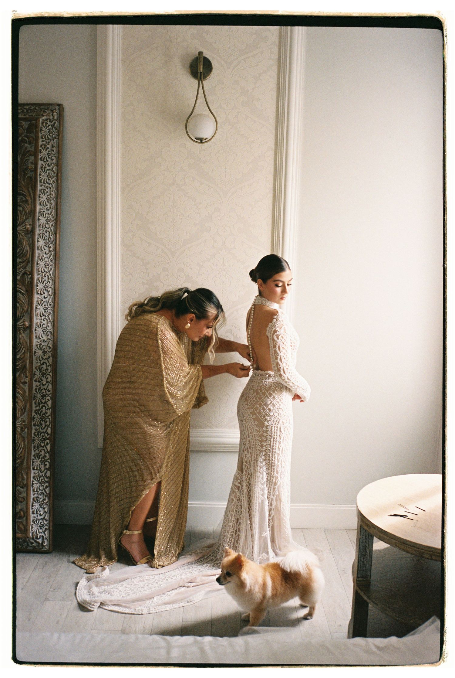 Final wedding dress fitting with seamstress making adjustments to a beaded gown.