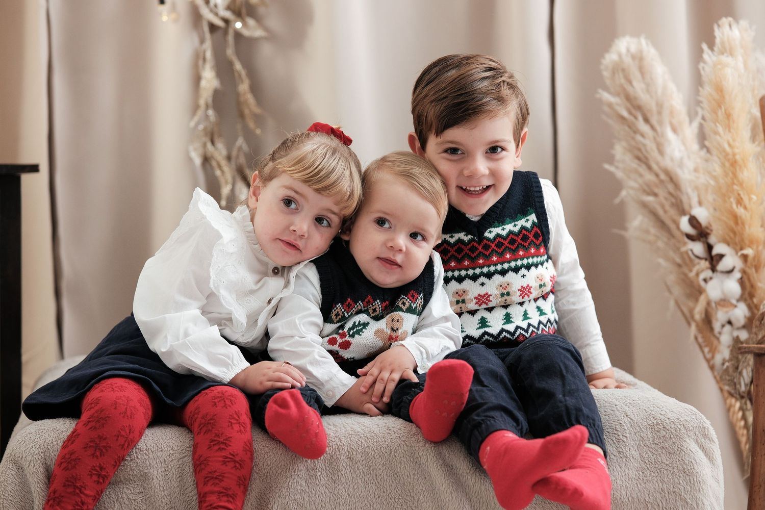 Family members in coordinated holiday outfits cuddling together on gray couch.