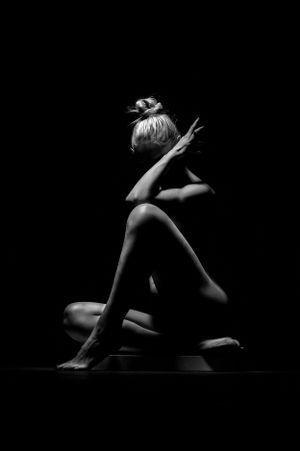 Artistic black and white nude photography with dramatic pose and lighting.