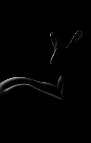 Minimalist bodyscape photography emphasizing curves and shadows in black and white.