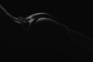 Artistic black and white silhouette of a curved line against dark background.