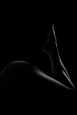 Dramatic light and shadow play creating abstract shapes on skin.
