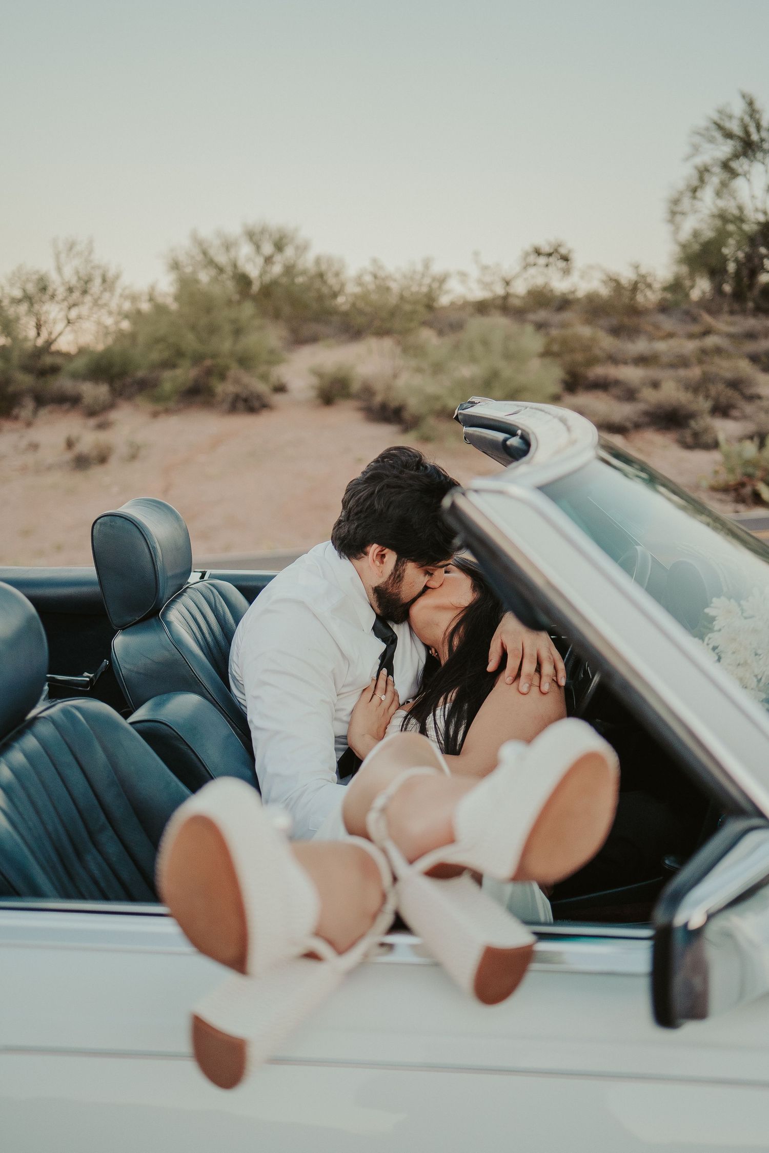 Couple sharing an intimate moment in a classic convertible car.