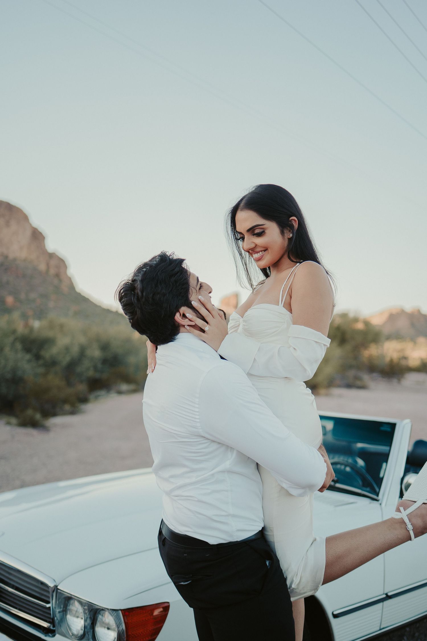 Romantic desert photoshoot featuring a couple in formal wear with vintage Mercedes.