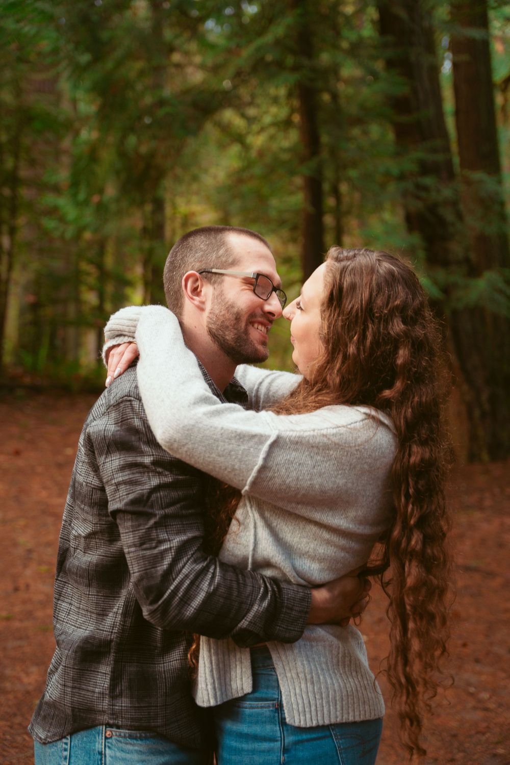 Couple sharing an intimate moment while embracing in an autumn forest setting with a warm natural background.