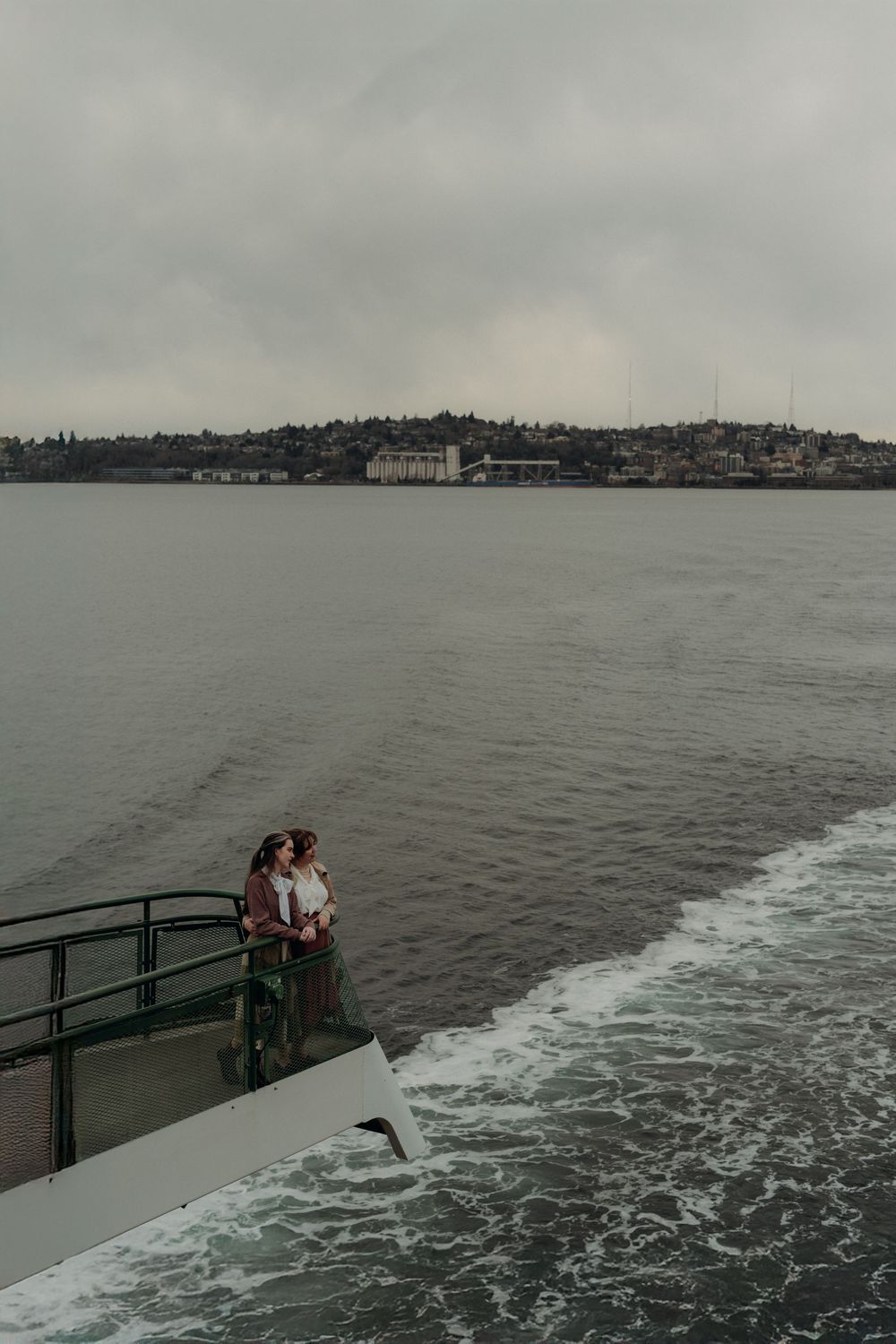 A sequence of photos showing a couple enjoying views from a ferry boat deck on an overcast day on the water.