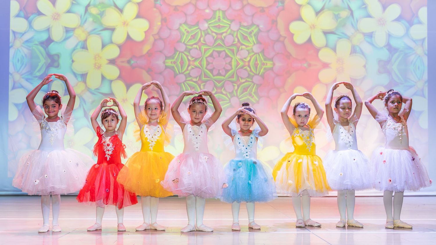 Young ballet students posing gracefully in matching white tutus during a school recital shoot in Dubai