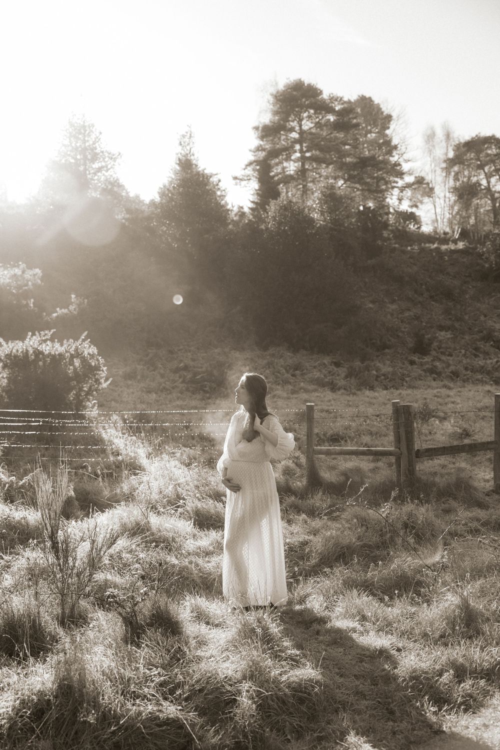 A dreamy black and white photo series of a person in a white dress walking through a misty meadow at sunset.