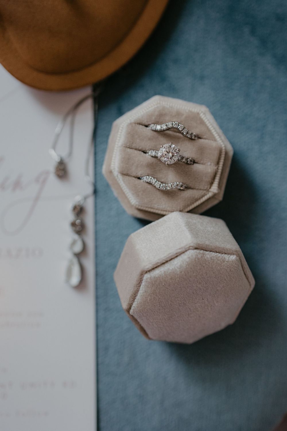 Three sparkling diamond engagement rings displayed in a beige velvet octagonal ring box on a blue surface.