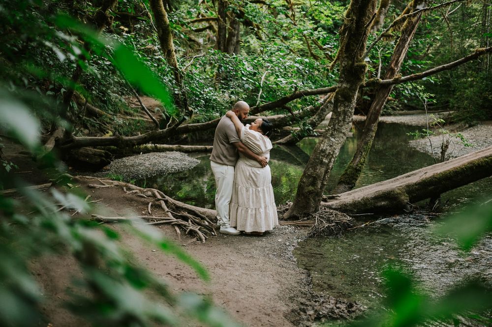 Photo of engaged couple hugging in front of creek in forest Cathedral Groves, MacMillan Park. Vancouver Island adventure photographer
