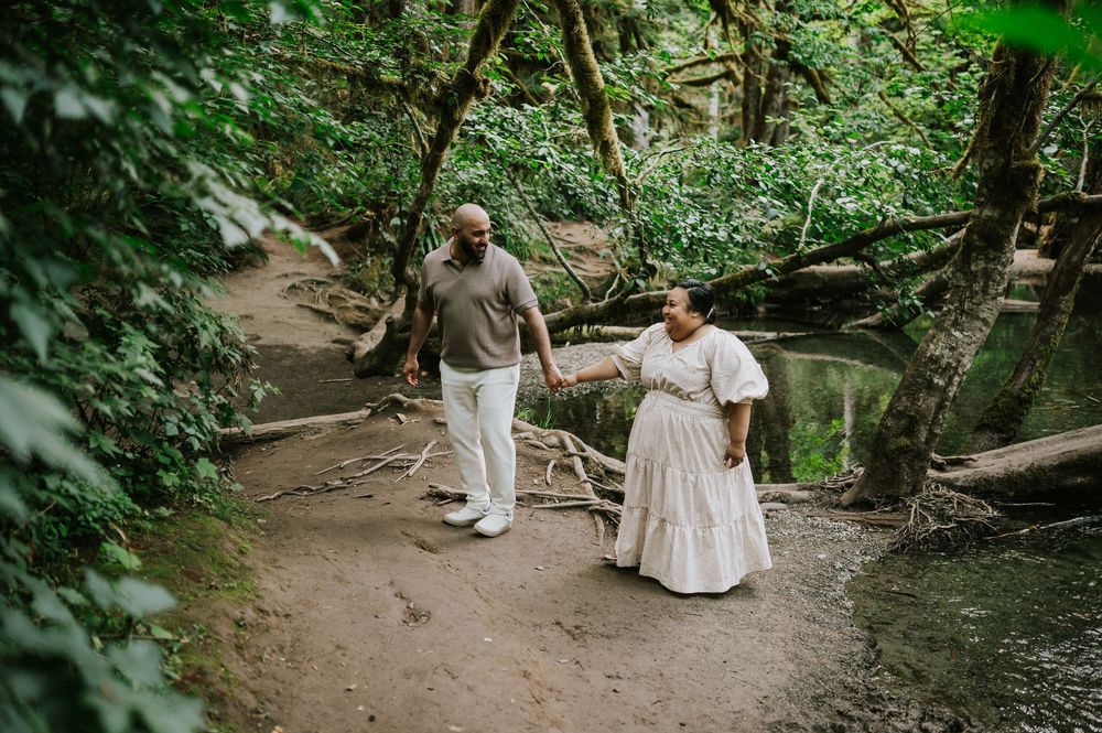 Photo of engaged couple walking in front of creek in forest Cathedral Groves, MacMillan Park. Vancouver Island adventure photographer