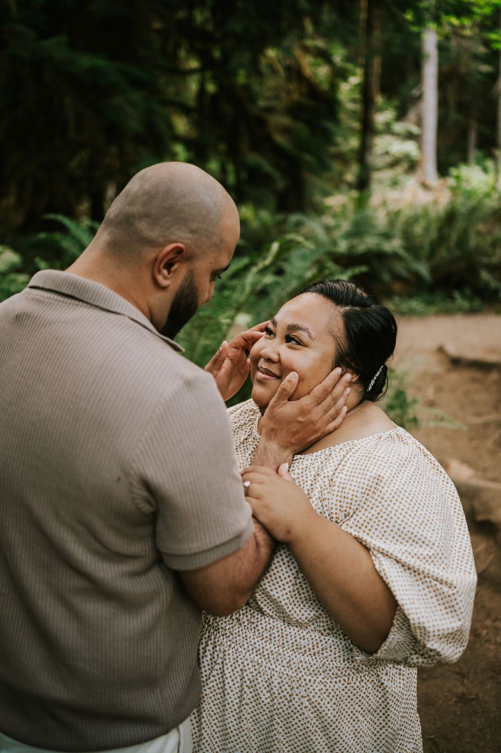 Photo of engaged couple holding each others face in Cathedral Groves, MacMillan Park forest trails. Vancouver Island adventure photographer