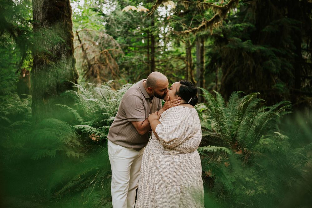 Photo of engaged couple kissing in ferns of Cathedral Groves, MacMillan Park forest trails. Vancouver Island adventure photographer