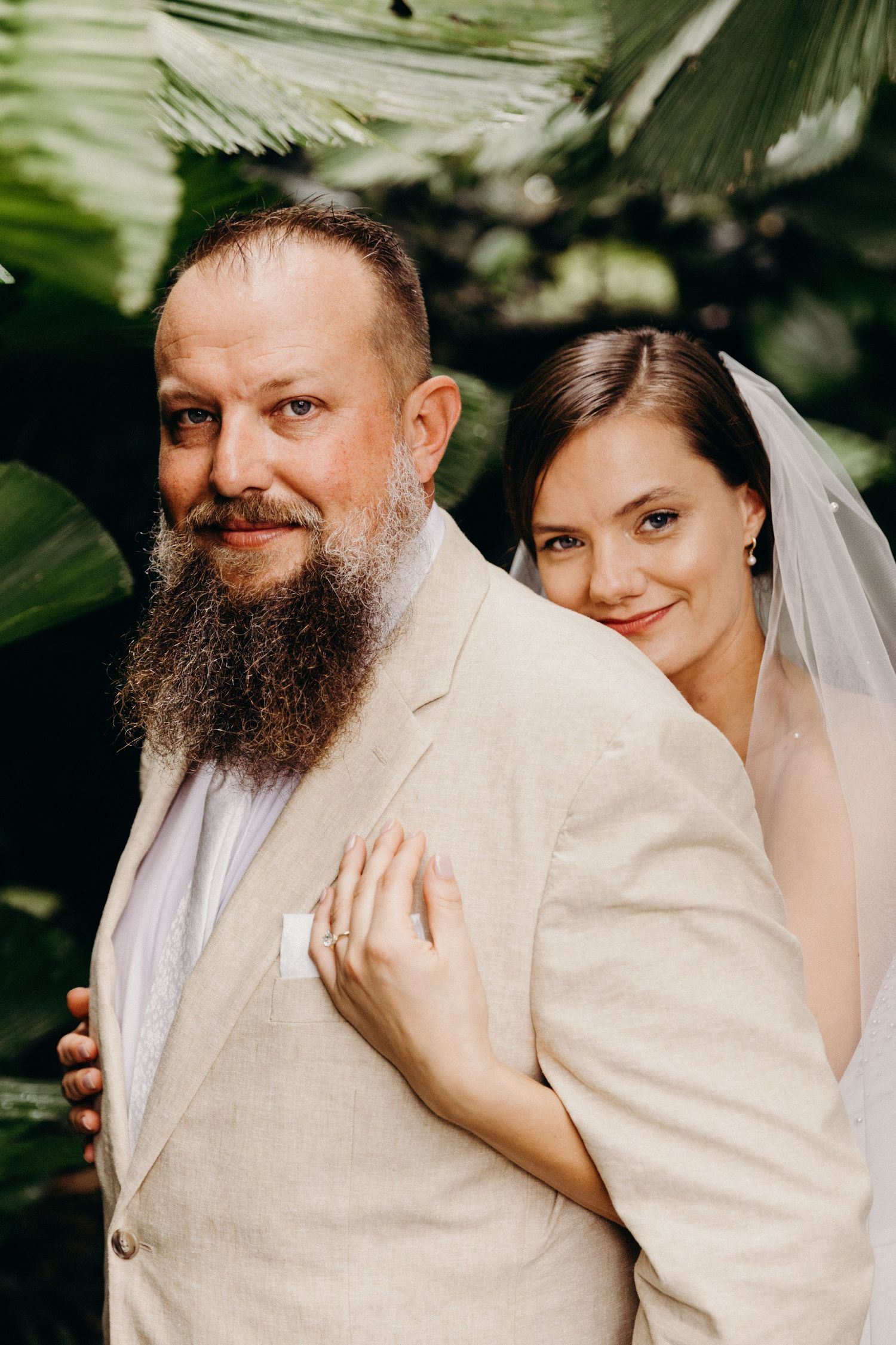 Intimate wedding portrait in a tropical garden setting with natural lighting.