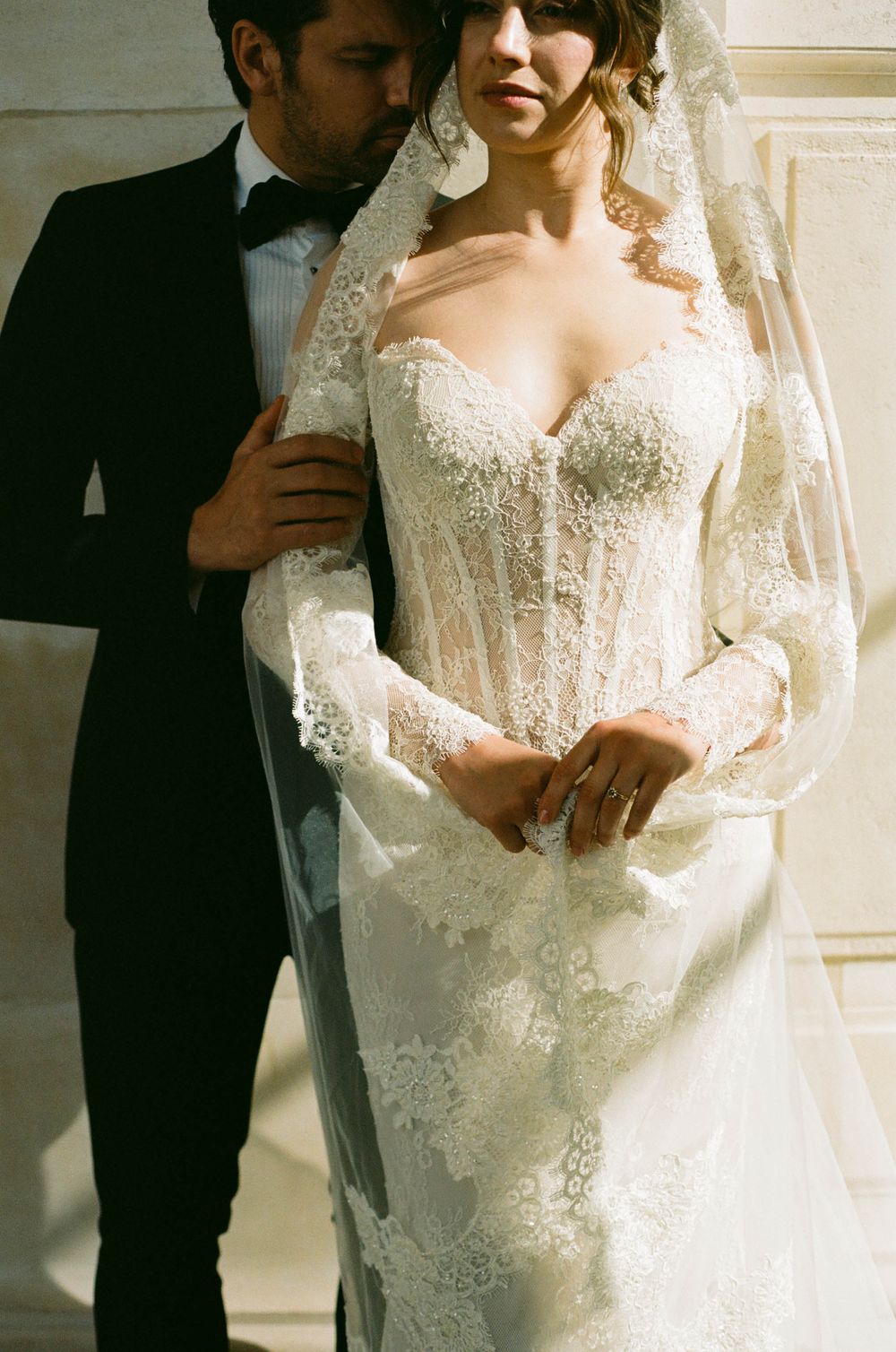 A wedding scene showing the close-up details of an intricate lace wedding gown in warm natural lighting. Paris wedding photography, paris
