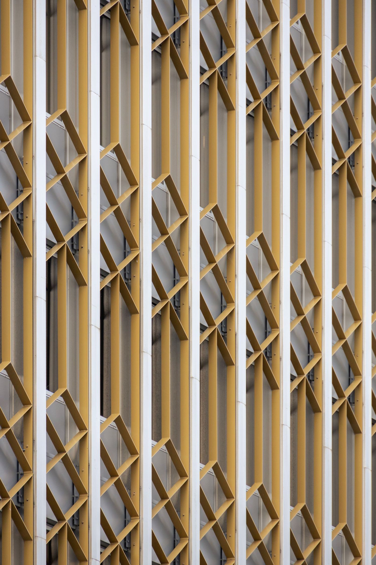 Facade of angled gold fins and white lattice panels creating a dynamic, textured rhythm across a building exterior.