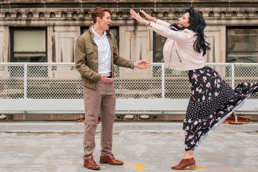 A playful couple dances on an urban rooftop with the person in a polka dot dress striking a dramatic pose.
