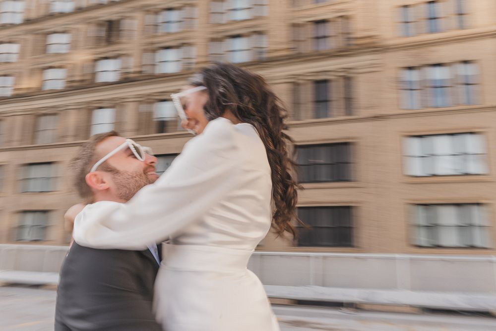 Two people share a romantic spin and embrace against a backdrop of classic architecture.