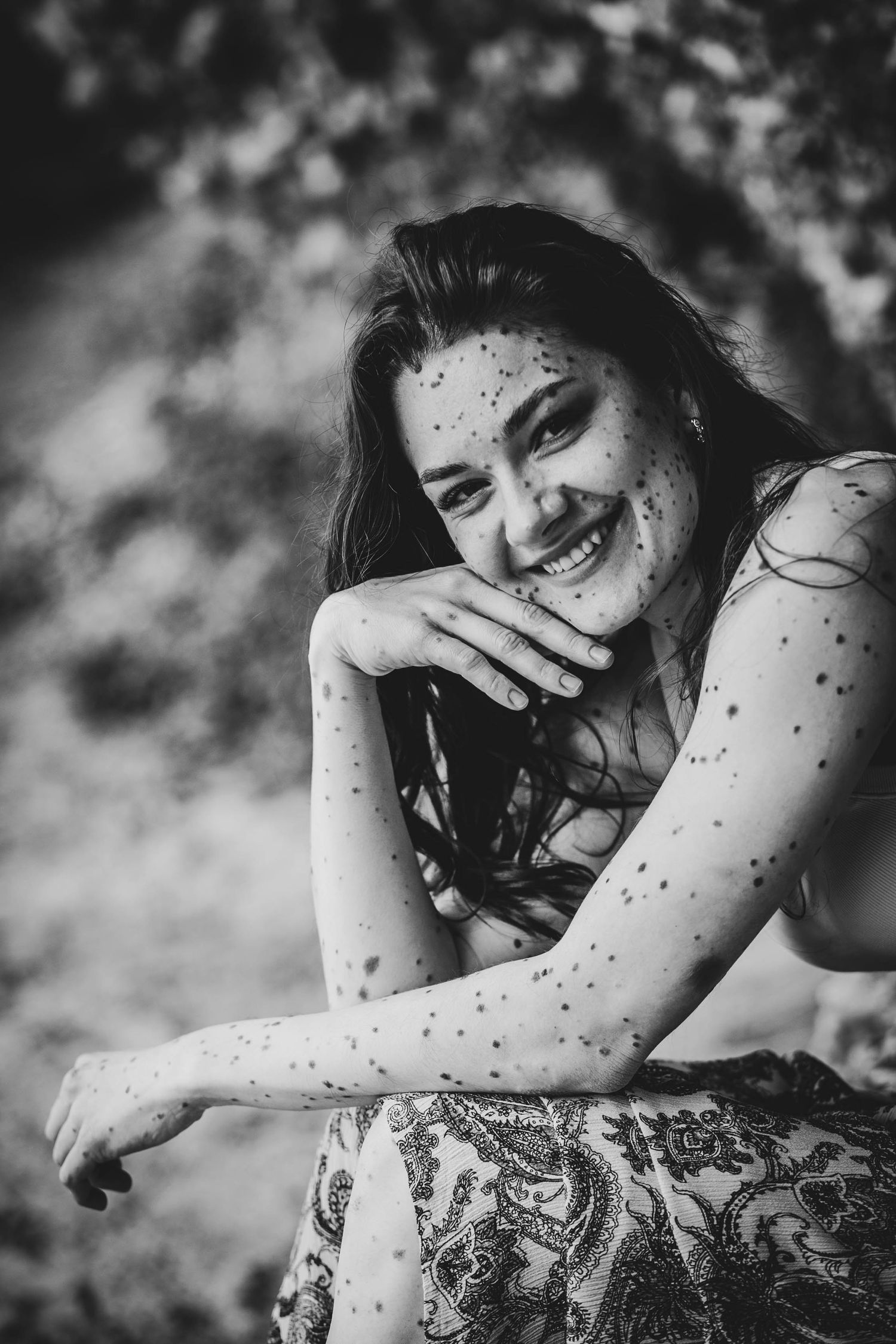 Black and white portrait of a joyful expression with speckled light creating a magical mood in natural outdoor setting.
