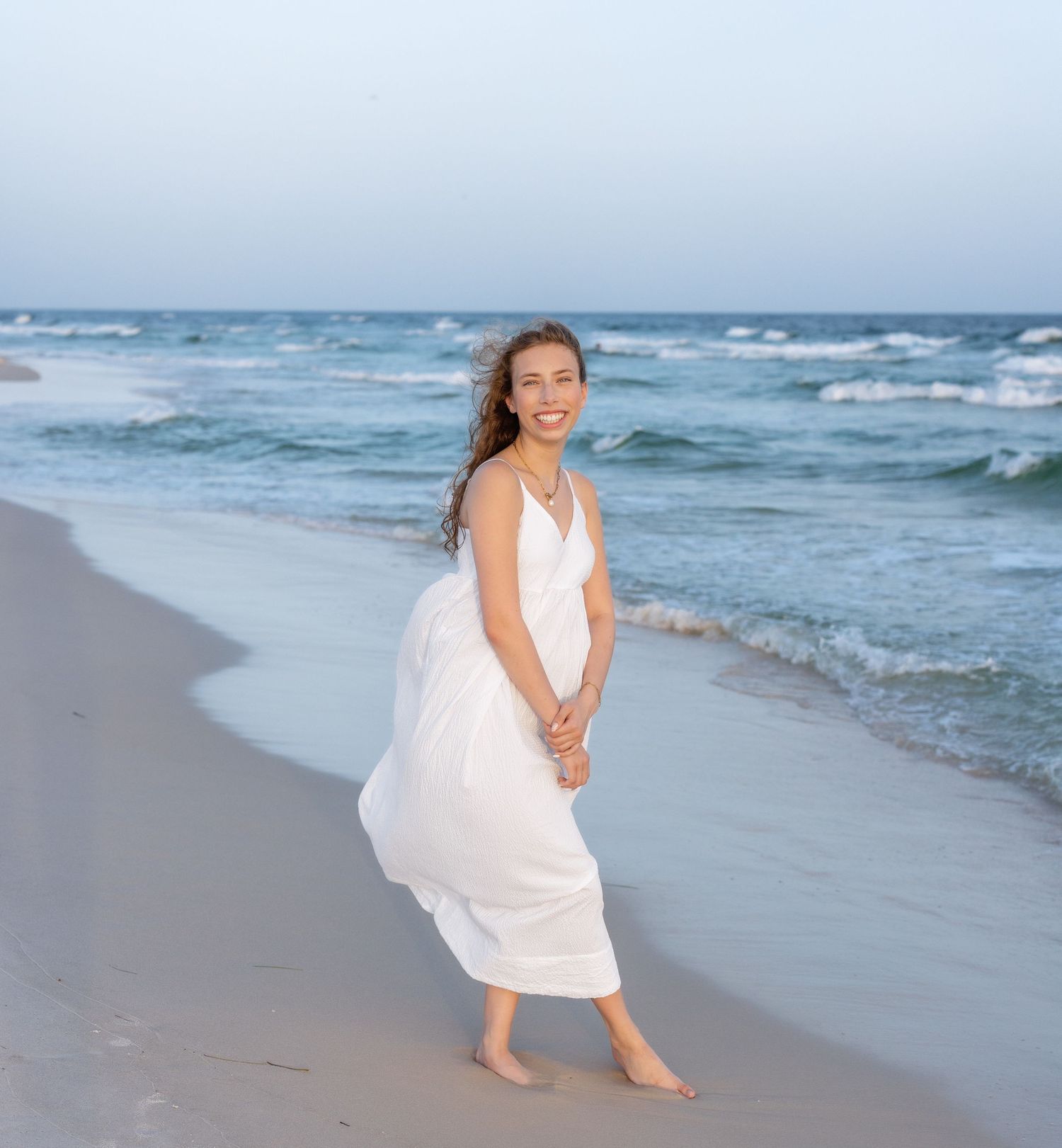 A flowing white dress catches the golden sunlight as wind sweeps through a summer meadow at sunset.